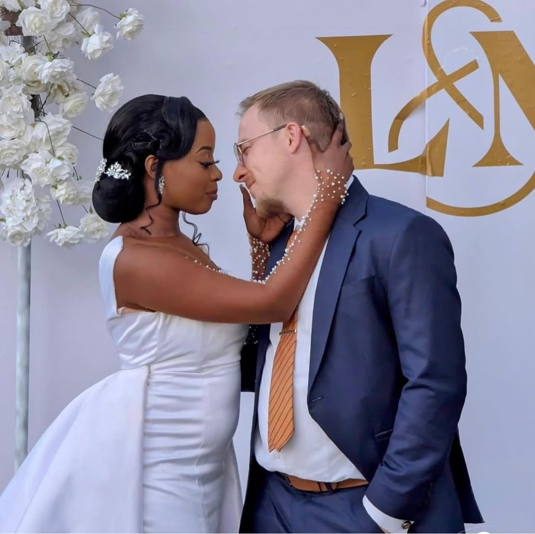 Bride and groom by their monogram backdrop